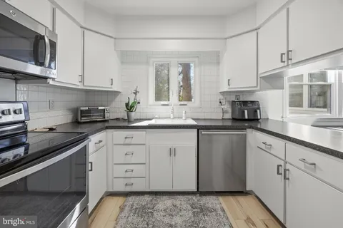 a kitchen with stainless steel appliances granite countertop a sink a stove and cabinets