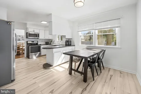 a kitchen with stainless steel appliances granite countertop a dining table chairs stove refrigerator and microwave