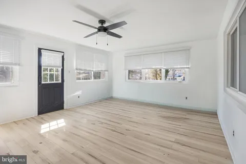 a view of an empty room with a window and wooden floor