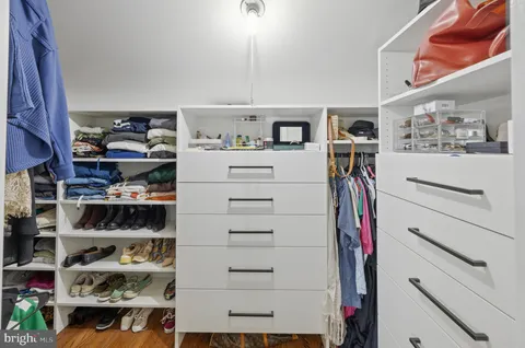a view of walk in closet with clothes and shoes