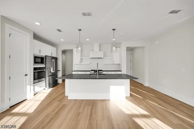 a large kitchen with stainless steel appliances kitchen island granite countertop a large counter top and a stove top oven