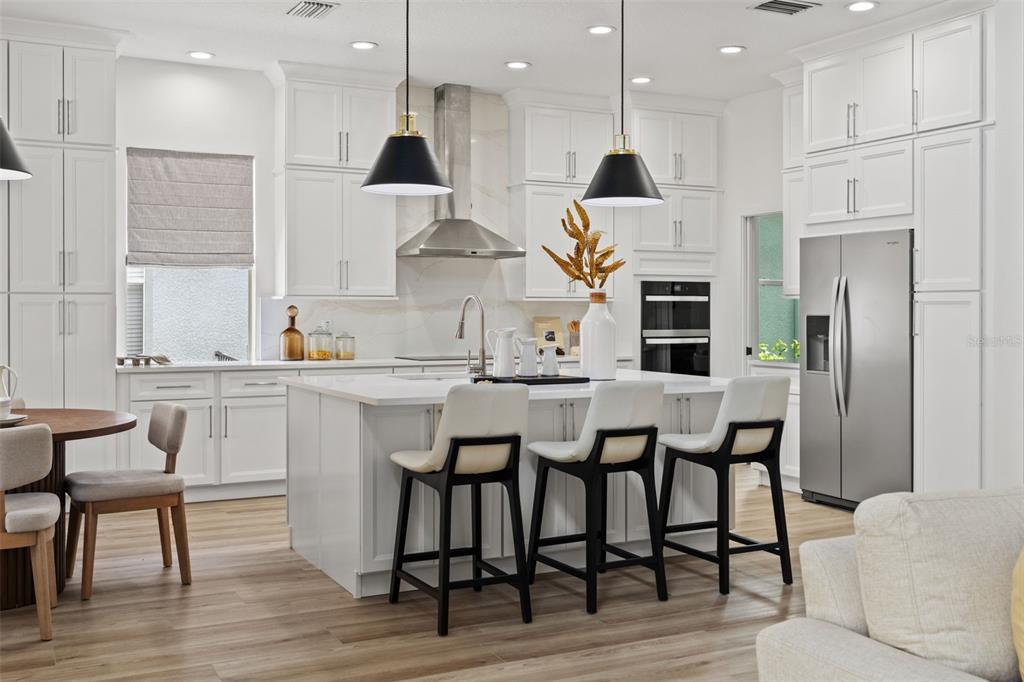 11627 Renaissance View Court Tampa, FL 33626 - Photo 36 of 62 a kitchen with stainless steel appliances granite countertop a kitchen island a stove a refrigerator a sink a dining table and chairs with wooden floor