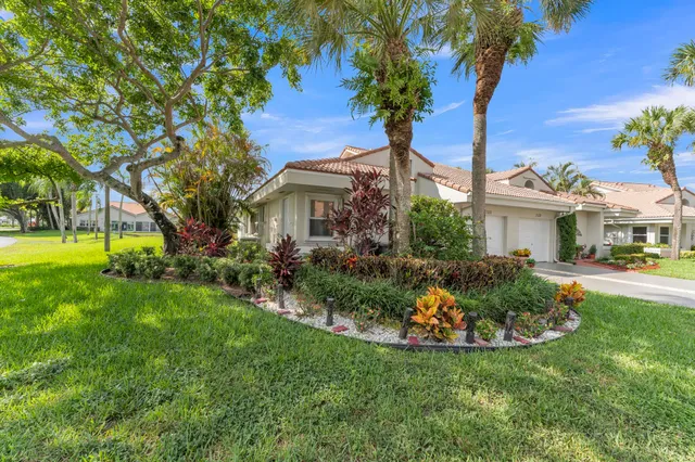 a front view of a house with garden and tree