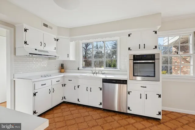a kitchen with granite countertop white cabinets stainless steel appliances a sink and a window