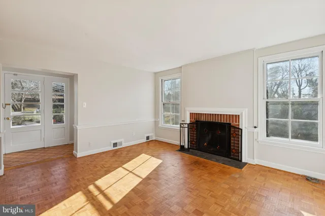 an empty room with windows and fireplace