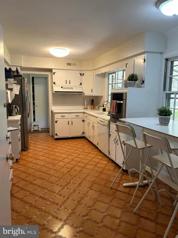 a large white kitchen with kitchen island white cabinets and stainless steel appliances