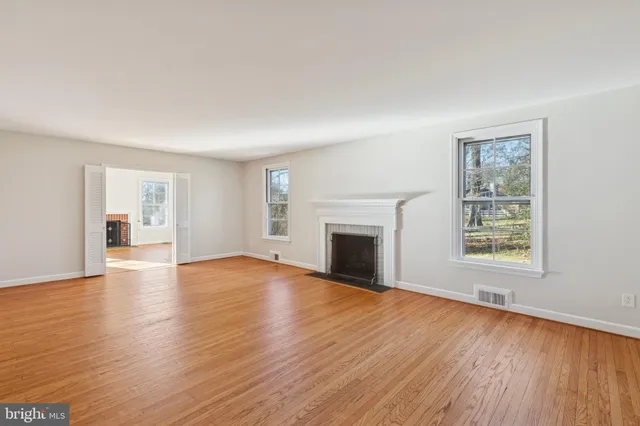 a view of empty room with wooden floor and fireplace