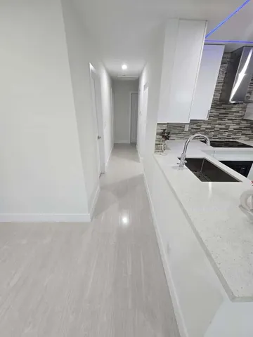 a view of a kitchen with a sink and dishwasher a stove top oven with wooden floor