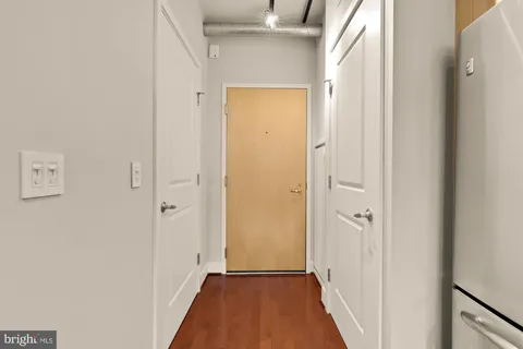 a view of a hallway with wooden floor and a bathroom