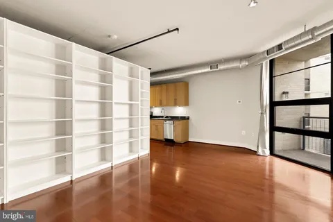 a view of an empty room with a window and wooden floor