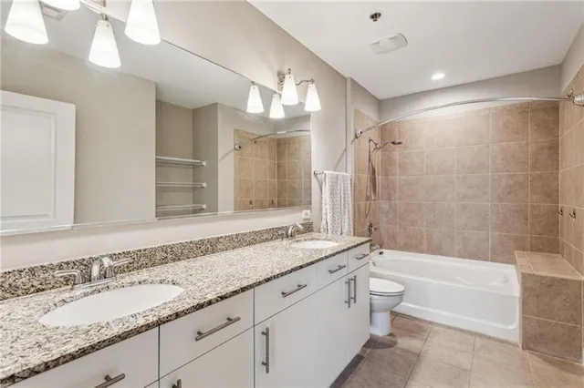 a bathroom with a granite countertop bathtub shower sink vanity and toilet