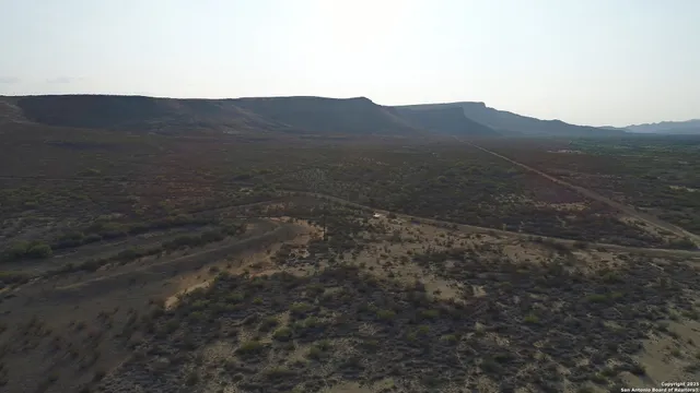 a view of a dry yard with mountains in the background