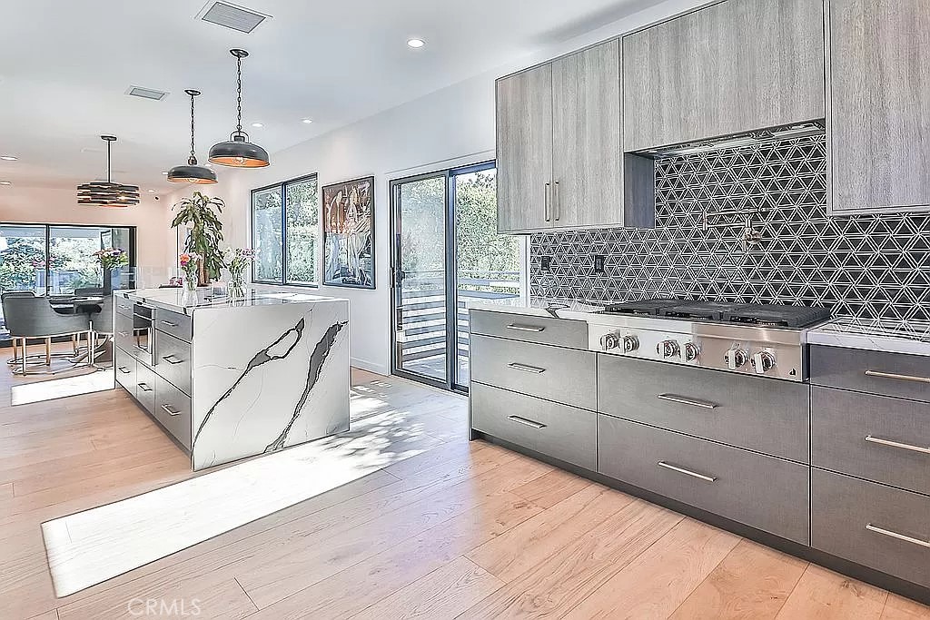 19532 Bermuda Street Porter Ranch, CA 91326 - Photo 19 of 74 a kitchen with stainless steel appliances granite countertop a stove a sink and white cabinets with wooden floor