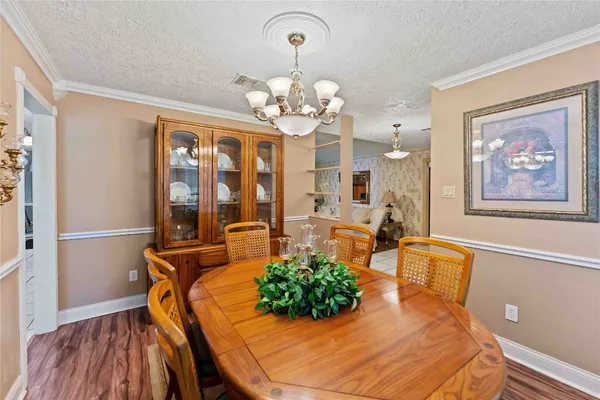 a dining room with wooden floor a chandelier a wooden table and chairs