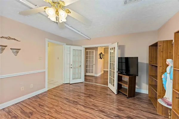 a view of a livingroom with a flat screen tv wooden floor and a ceiling fan