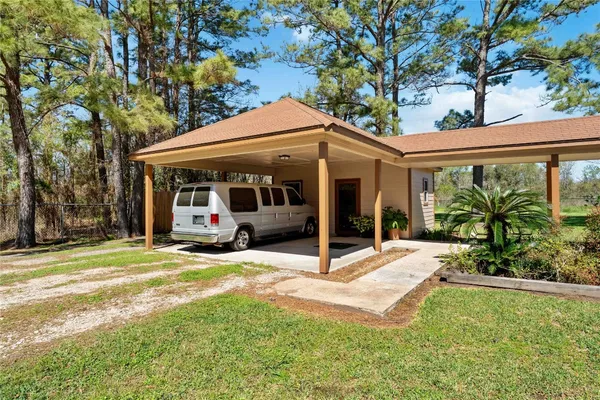 a view of a patio with table and chairs under an umbrella with large trees