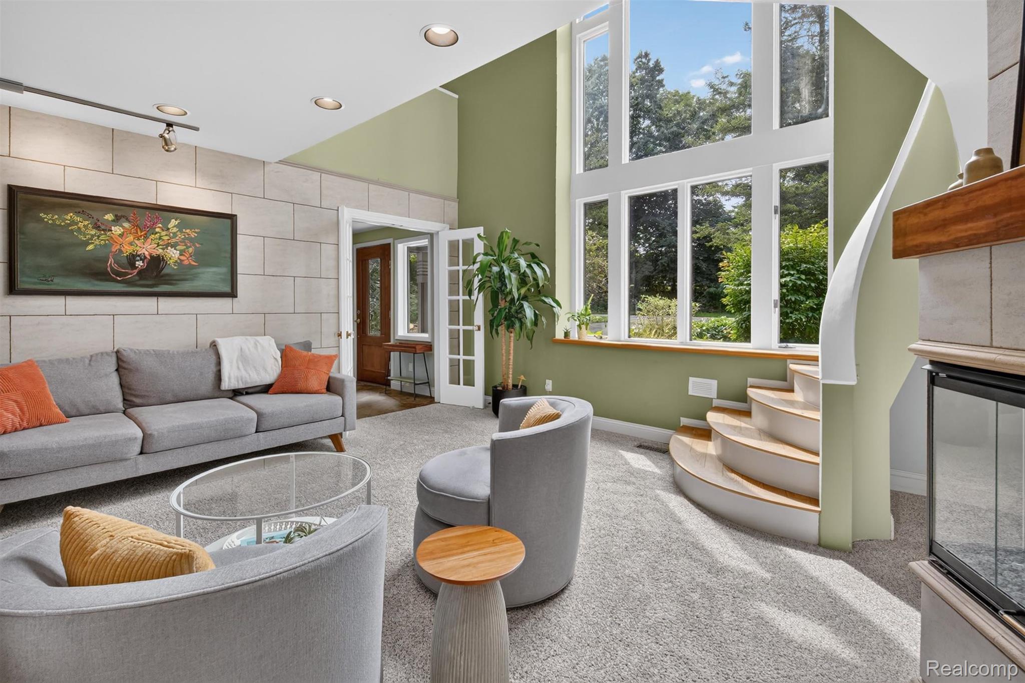 Floor-to-ceiling windows, curved staircase, recessed lighting, stone-finish accent wall, and built-in fireplace
