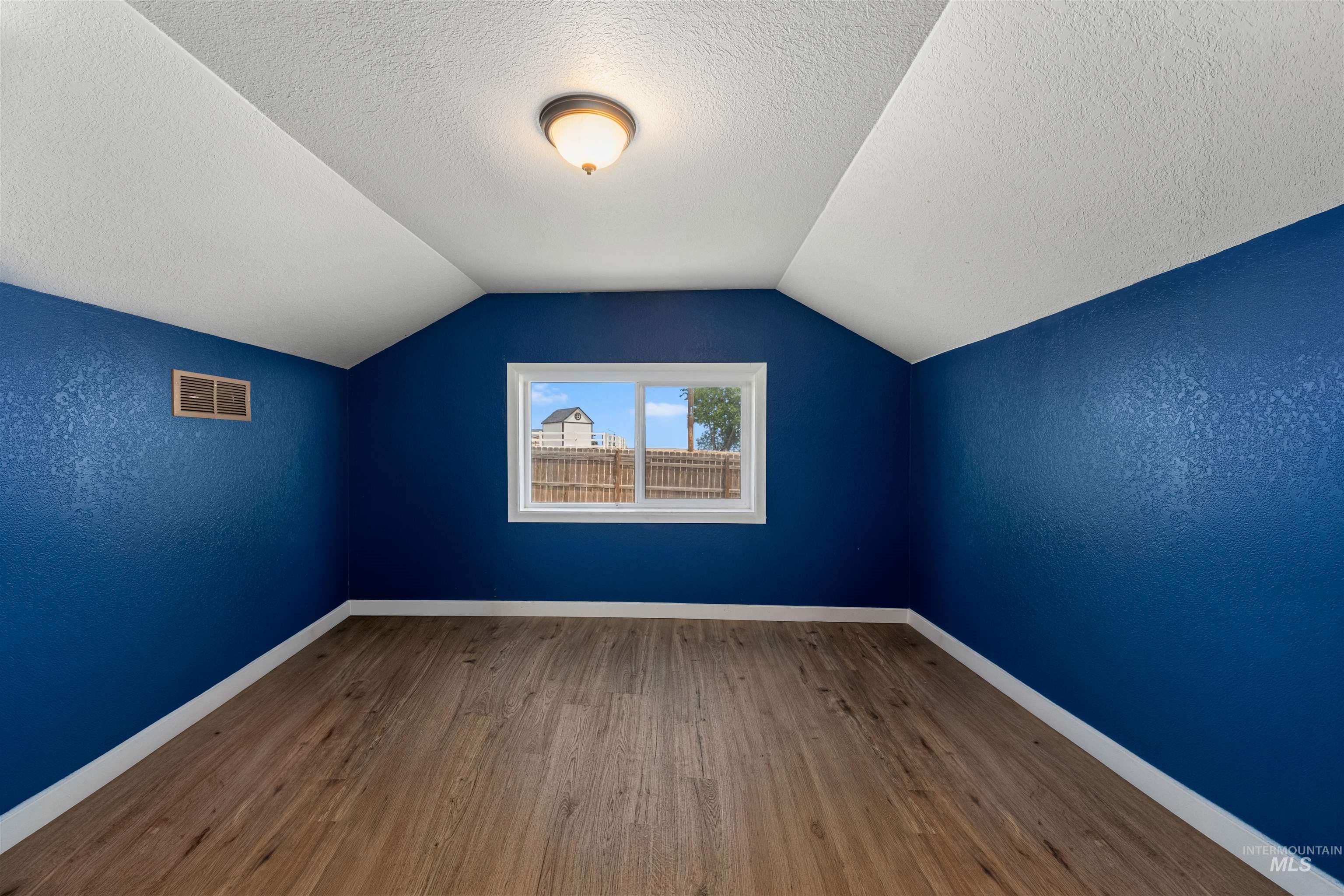 17441 Upper Pleasant Ridge Road Caldwell, ID 83607 - Photo 6 of 40 Bright room featuring wood-finish flooring, a white trim baseboard, and a central window with a white frame