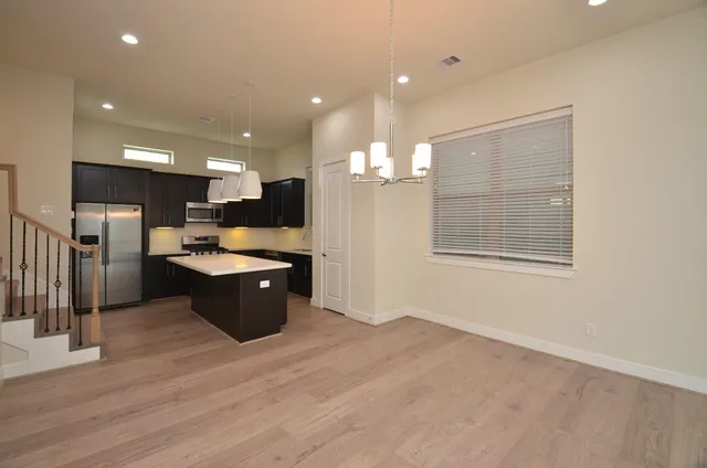 a large kitchen with a large counter top a sink stainless steel appliances and cabinets