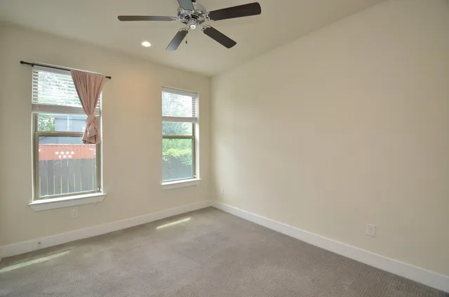 an empty room with windows and fan