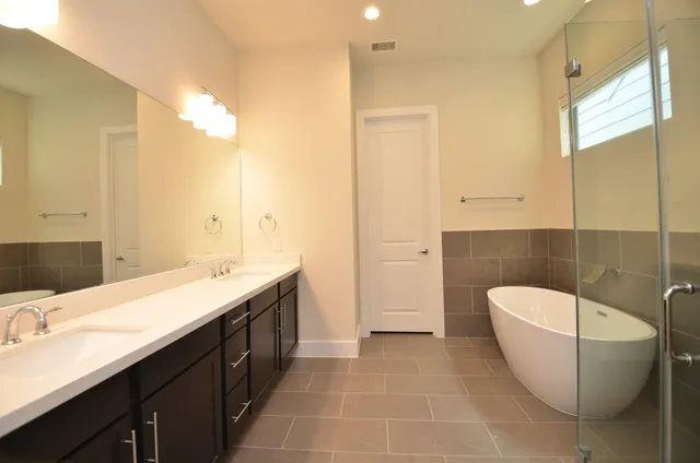 a spacious bathroom with a double vanity sink a mirror and a bathtub