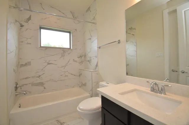 a bathroom with a granite countertop sink a toilet a mirror and bathtub