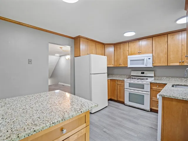 a kitchen with granite countertop wooden cabinets and a refrigerator