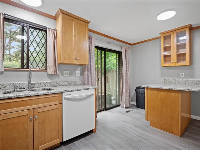 a kitchen with kitchen island granite countertop wooden cabinets a stove a sink and a large window