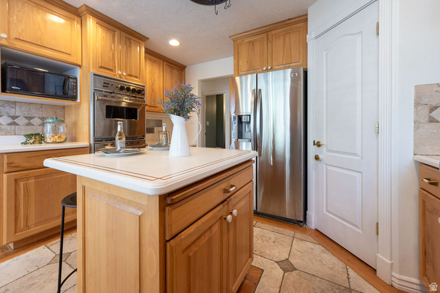 875 East 1300th Street North Mapleton, UT 84664 - Photo 19 of 65 Kitchen with decorative backsplash, stainless steel appliances, light countertops, a kitchen bar, and a textured ceiling