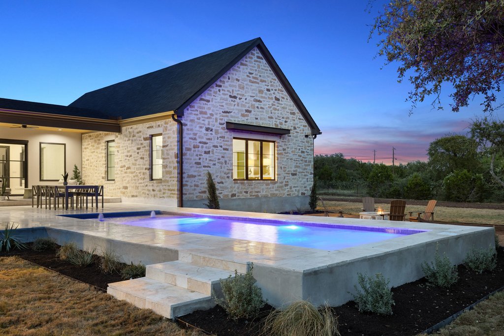 9207 Zyle Road Austin, TX 78737 - Photo 37 of 40 An inviting pool with integrated lighting complements this home's stone exterior and expansive patio.