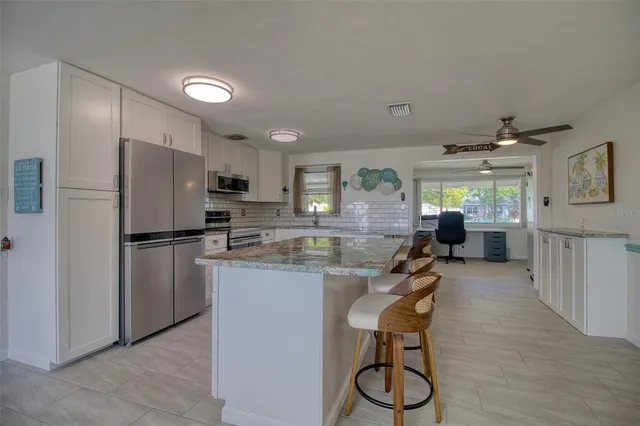 a kitchen with granite countertop a table chairs stove a sink dishwasher and cabinets