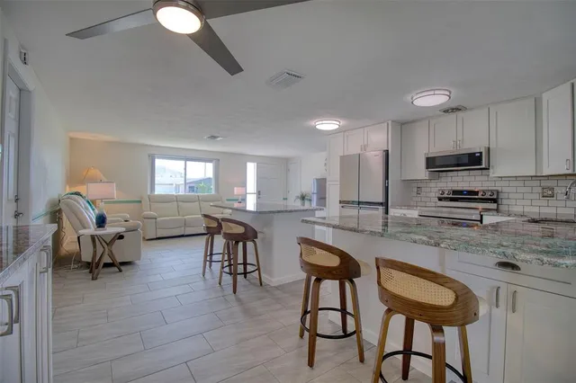 a kitchen with stainless steel appliances granite countertop a table chairs sink refrigerator and cabinets