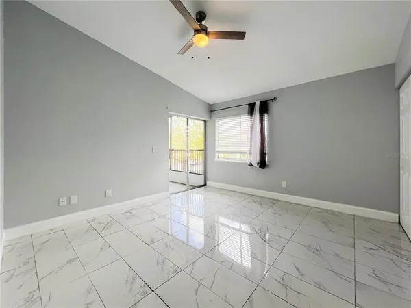 an empty room with windows and fan