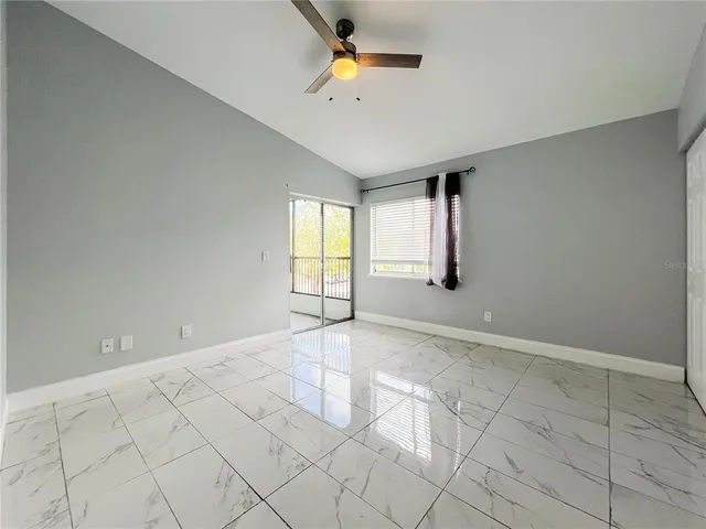 an empty room with windows and fan