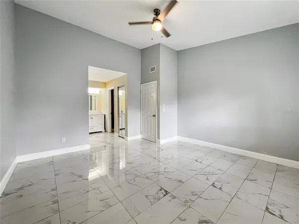 an empty room with windows and fan