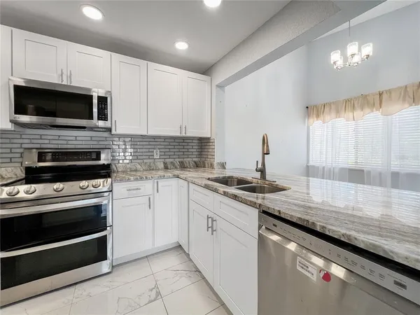 a kitchen with stainless steel appliances granite countertop a sink and a stove