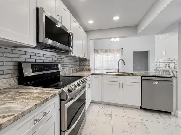 a kitchen with stainless steel appliances granite countertop a stove top oven a sink and a microwave
