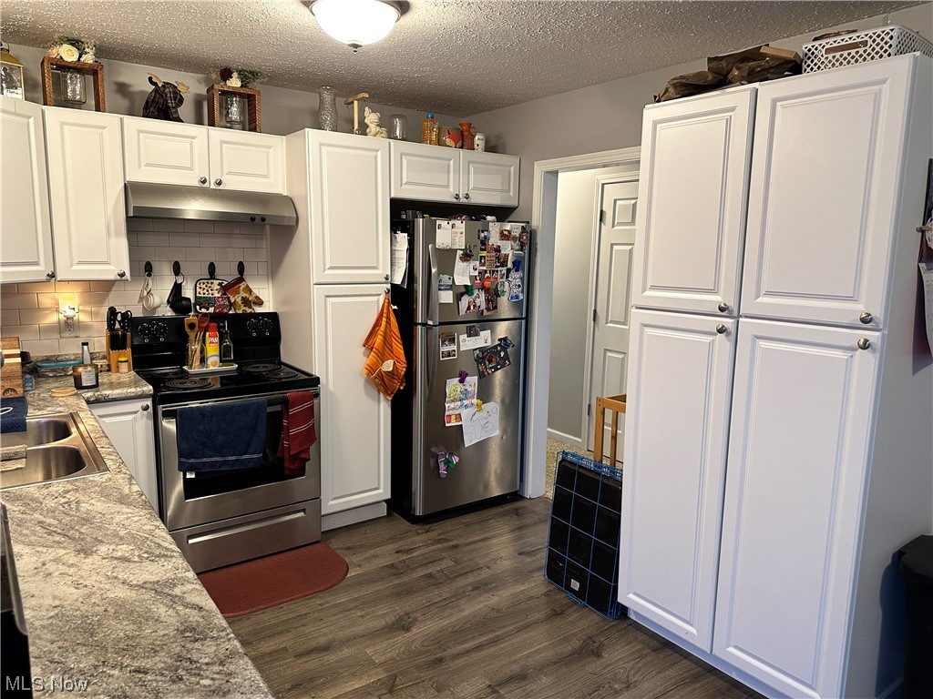 17 Sychar Road Mount Vernon, OH 43050 - Photo 10 of 27 Kitchen with appliances with stainless steel finishes, white cabinetry, light stone countertops, dark wood-type flooring, and backsplash