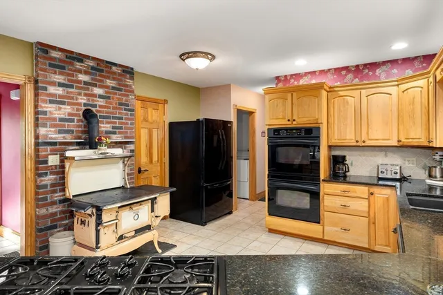 a kitchen with stainless steel appliances kitchen island granite countertop a refrigerator and a stove top oven