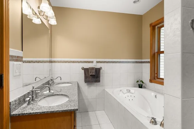 a bathroom with a granite countertop sink and a bathtub