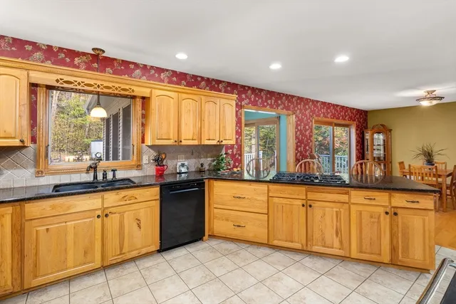 a large kitchen with granite countertop a sink and white cabinets