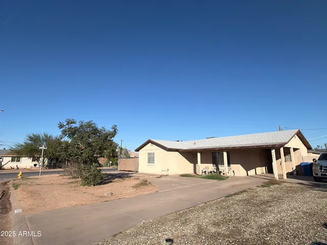 a front view of a house with a dirt yard and a large tree