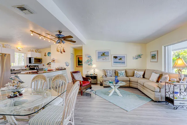 a living room with furniture kitchen view and a wooden floor