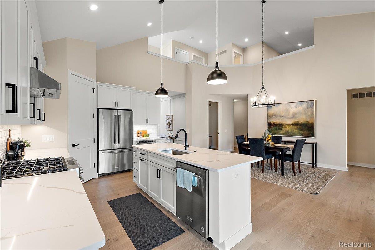 2032 Breckenridge Court, Unit 9 Rochester, MI 48309 - Photo 12 of 39 Kitchen featuring a towering ceiling, tasteful backsplash, stainless steel appliances, white cabinetry, and an island with sink