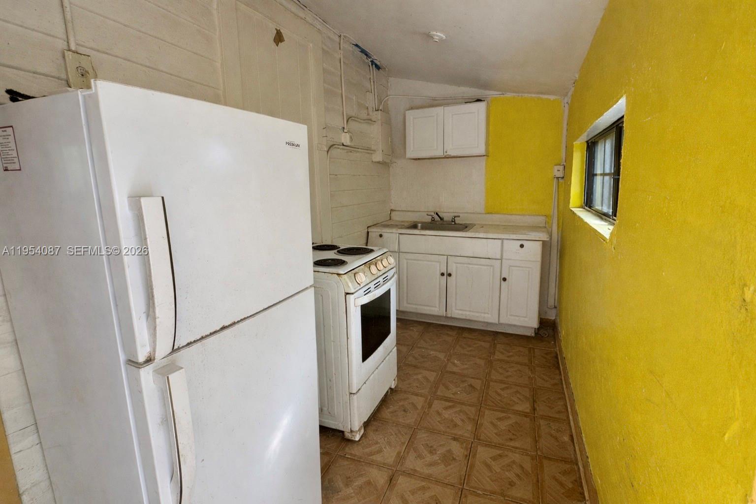 3748 Washington Avenue Miami, FL 33133 - Photo 10 of 15 a kitchen with a refrigerator a stove top oven and a sink