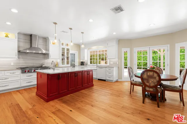 a kitchen with stainless steel appliances granite countertop a stove top oven a sink dishwasher a dining table and chairs with wooden floor