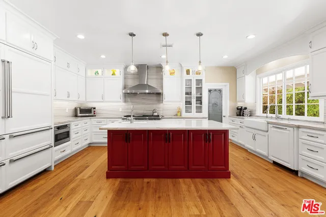 a kitchen with stainless steel appliances kitchen island granite countertop wooden floors wooden cabinets and sink