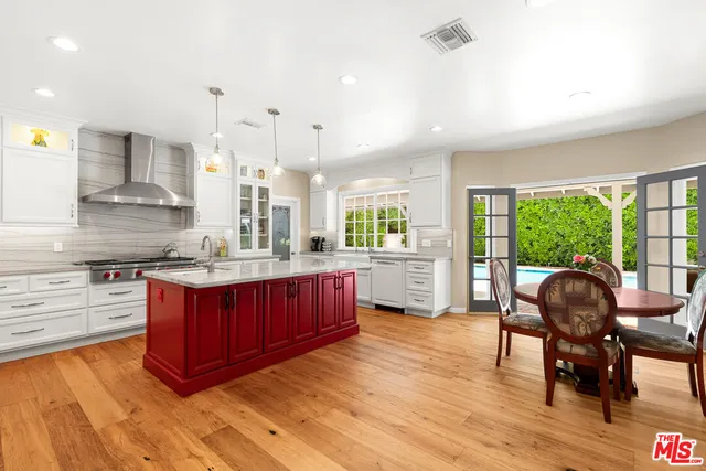 a kitchen with stainless steel appliances granite countertop wooden floors wooden cabinets dining table and chair