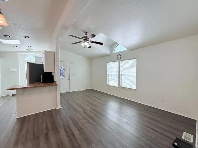 a view of an empty room with a window and wooden floor