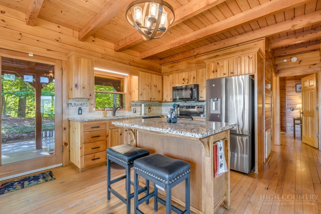 2229 Elk Ridge Road Ferguson, NC 28624 - Photo 14 of 42 a kitchen with stainless steel appliances granite countertop a refrigerator a stove top oven a sink dishwasher and dining table with wooden floor